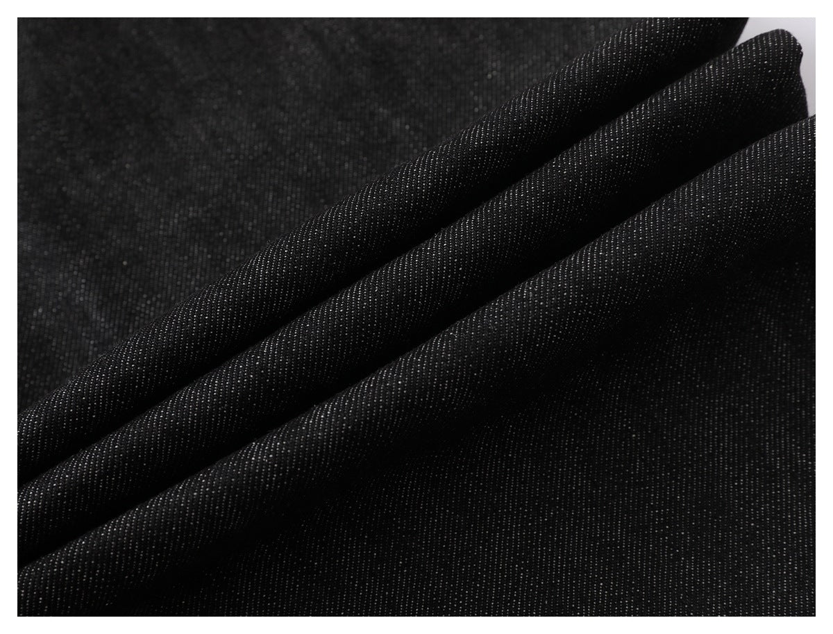 Close-up of black fabric with a fine, subtly textured weave, draped in diagonal folds.
