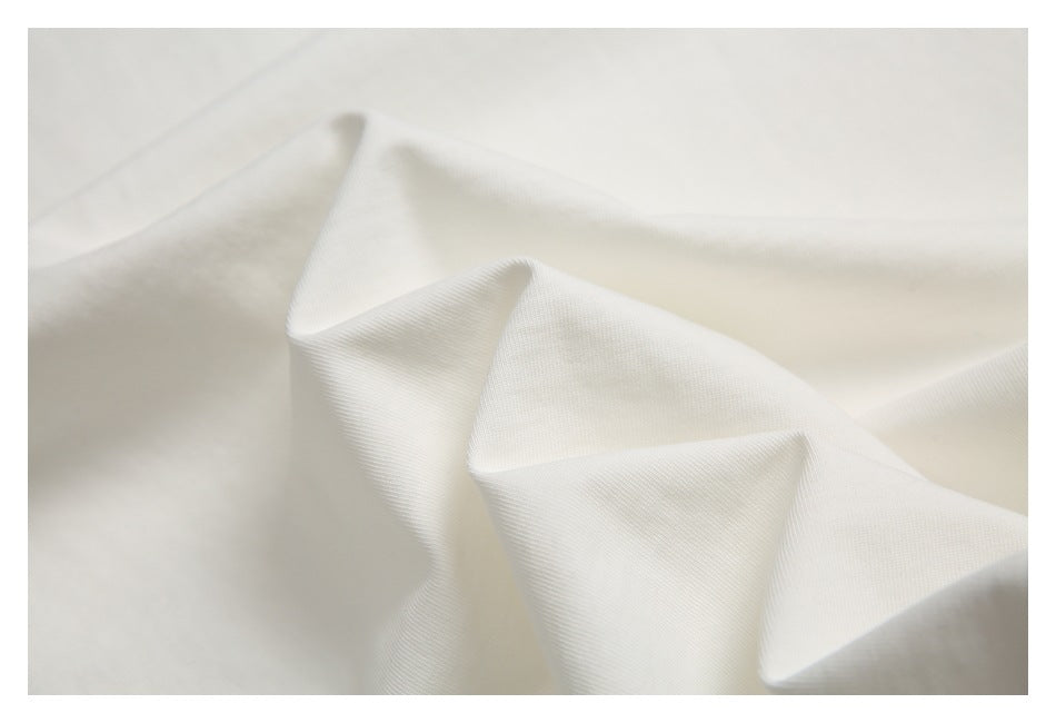 Close-up of ivory-white fabric draped into soft folds, showing a fine textured weave.