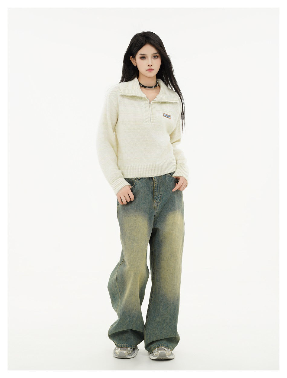 Full-length model wearing an ivory quarter-zip sweater, loose faded jeans, and sneakers.