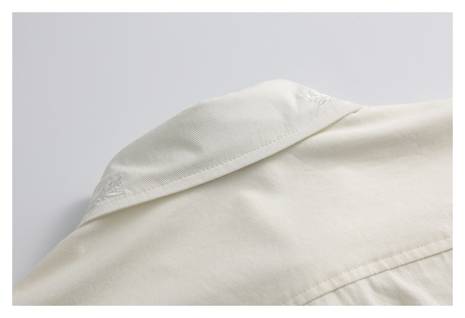 Close-up of an ivory shirt collar with small embroidered leaf details.