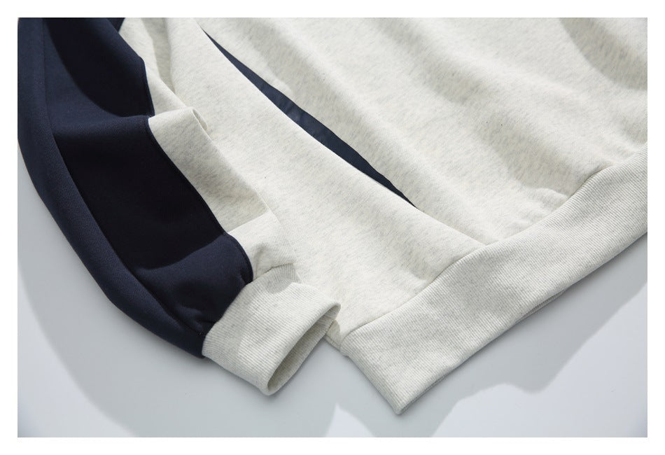 Close-up of a light gray sweatshirt with a navy sleeve panel and ribbed cuff and hem.