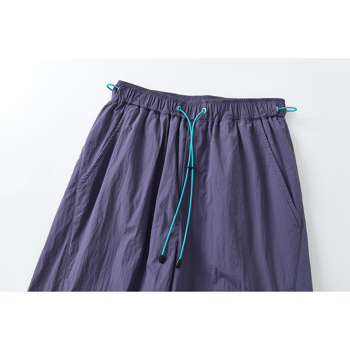 Close-up of purple wide-leg pants with an elastic waistband and bright turquoise drawcords.