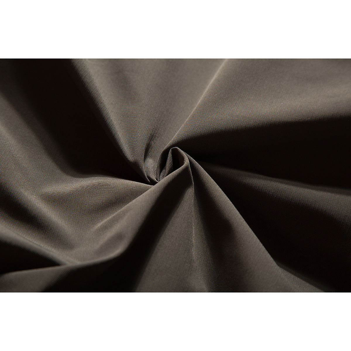 Close-up of charcoal-brown jacket fabric gathered into folds.