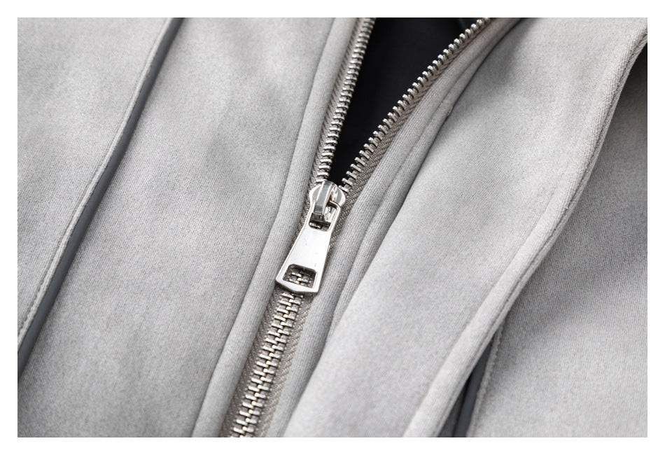 Close-up of a silver zipper on a light gray jacket with dark piping along the edge.