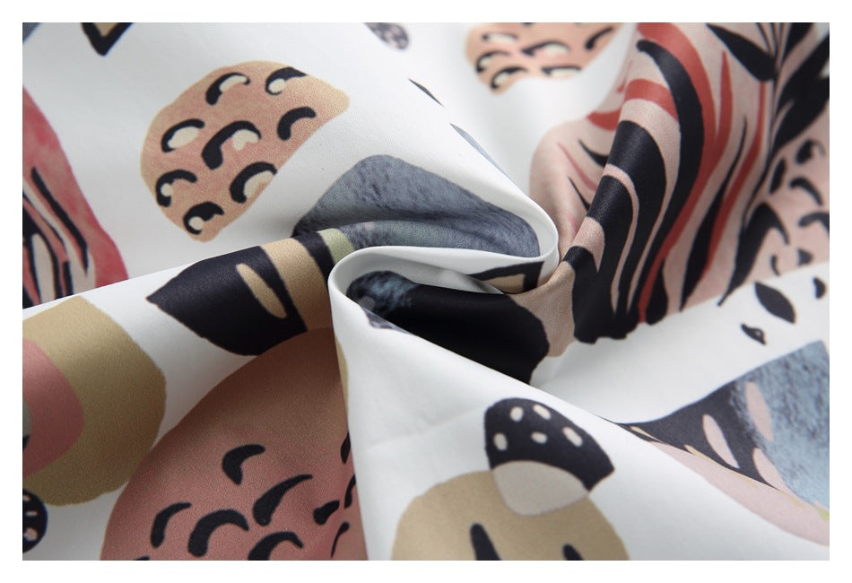 Close-up of draped white fabric with an abstract print in black, gray, tan, and muted pink.