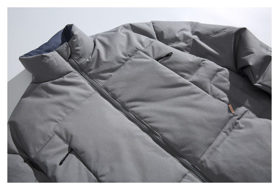 Close-up of a gray padded jacket showing its front zipper, high collar, stitched panels and zippered pockets.