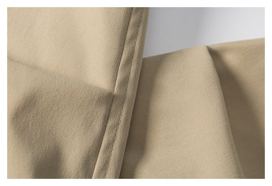 Close-up of beige fabric showing its diagonal weave and stitched seam.