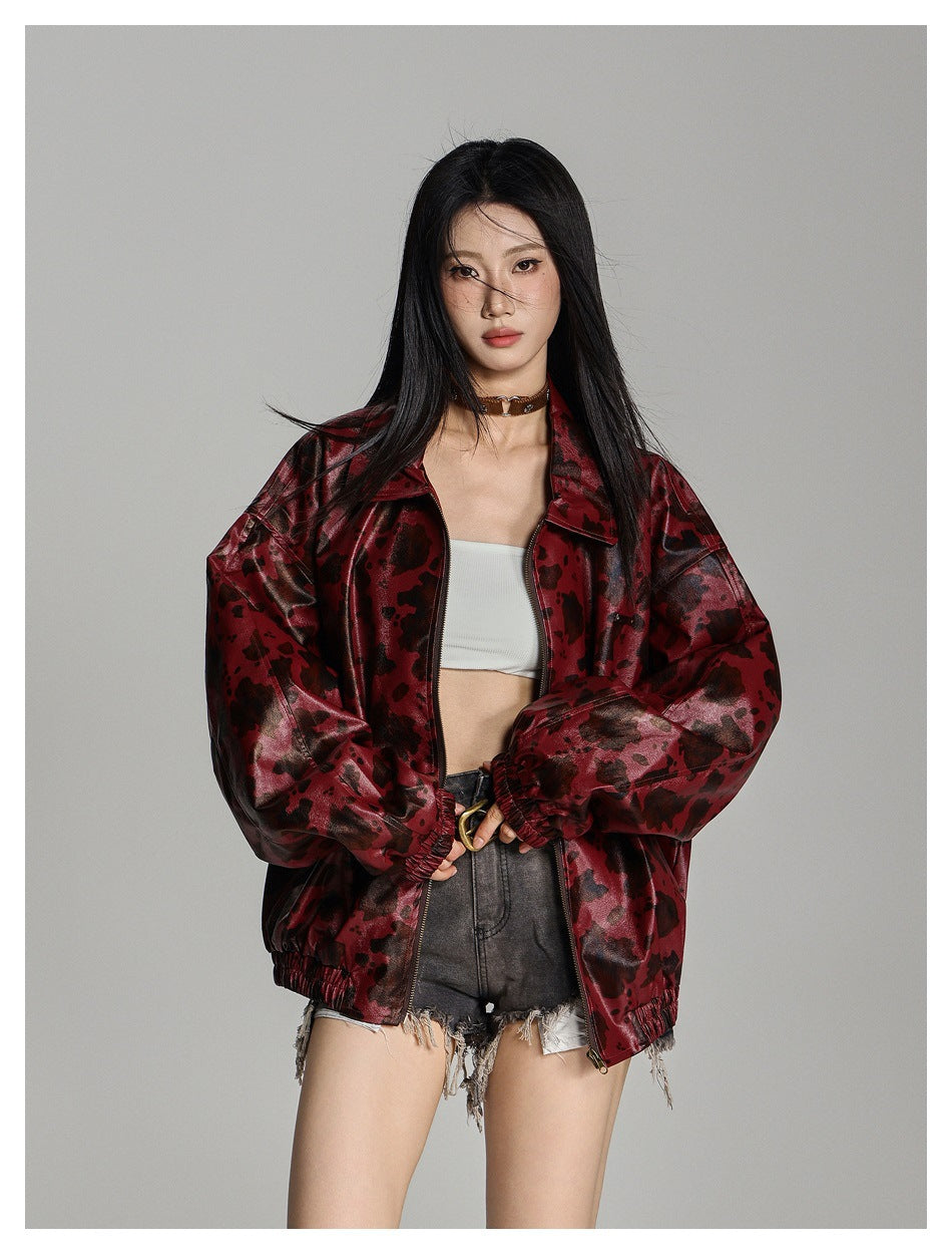 Model wearing an open oversized red animal-spot jacket with elastic cuffs over a white top and denim shorts