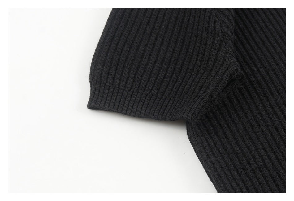 Close-up of the black ribbed sweater's short sleeve, cuff, and underarm seam.