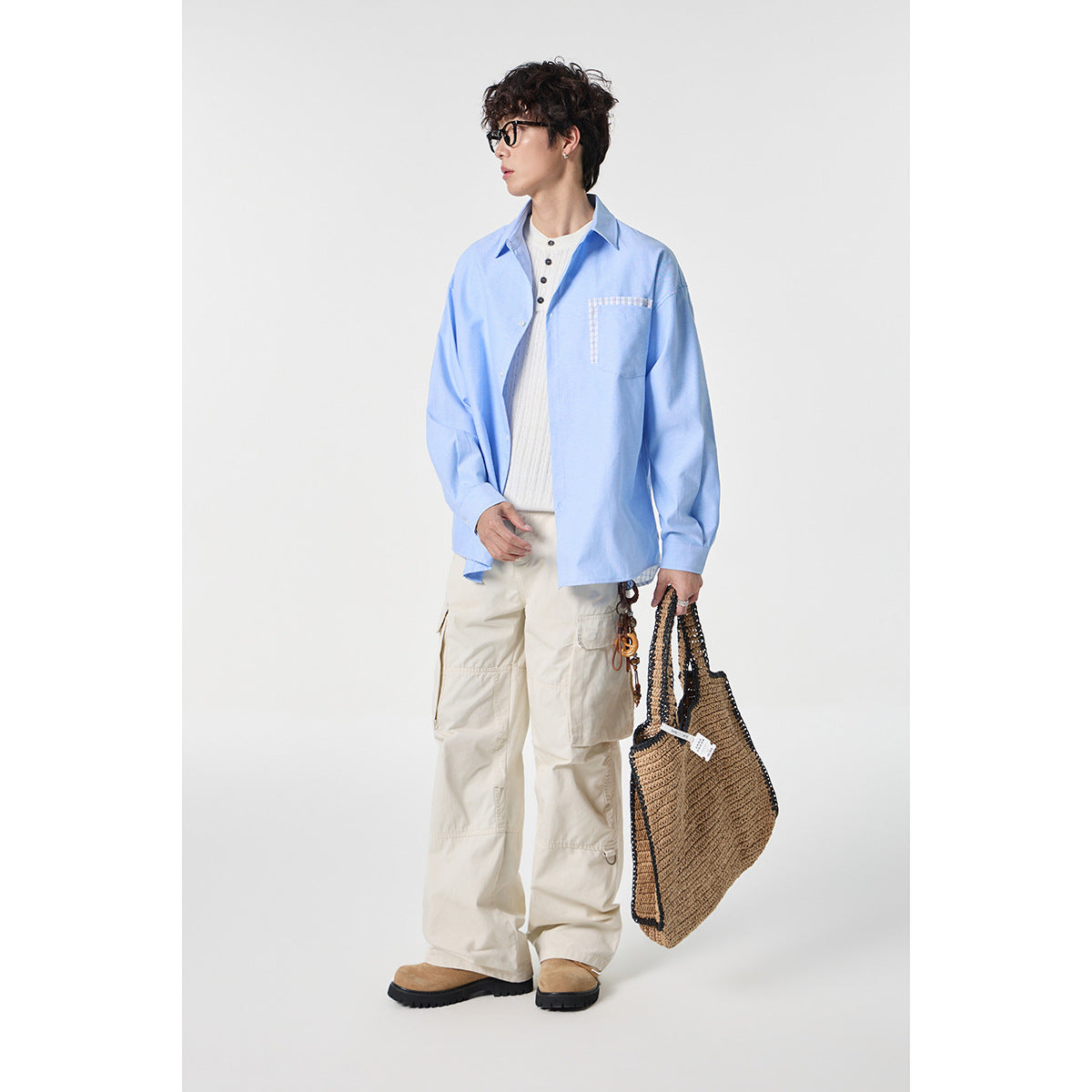Full-length model wearing a light blue button-up shirt with checked pocket trim and cream cargo pants.