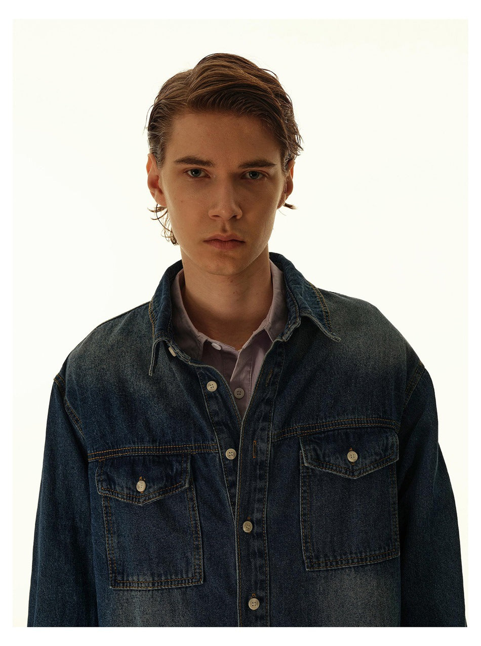 Close-up of a model in a dark blue denim shirt showing collar, button placket and two flap chest pockets