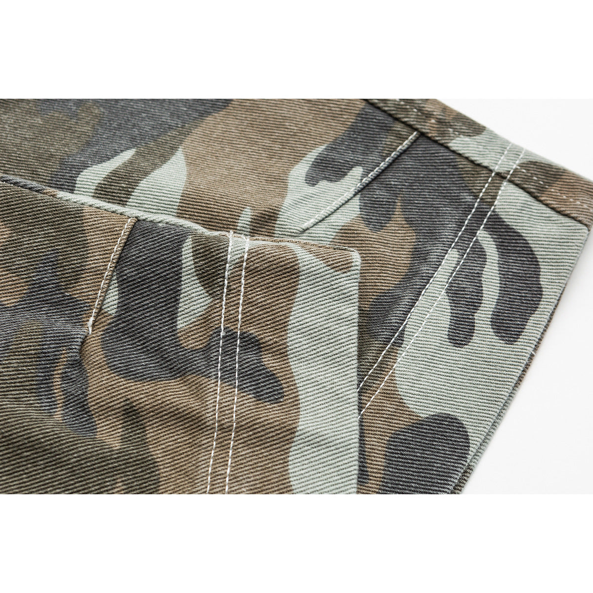 Close-up of camouflage trouser fabric with a stitched seam and panel edge.