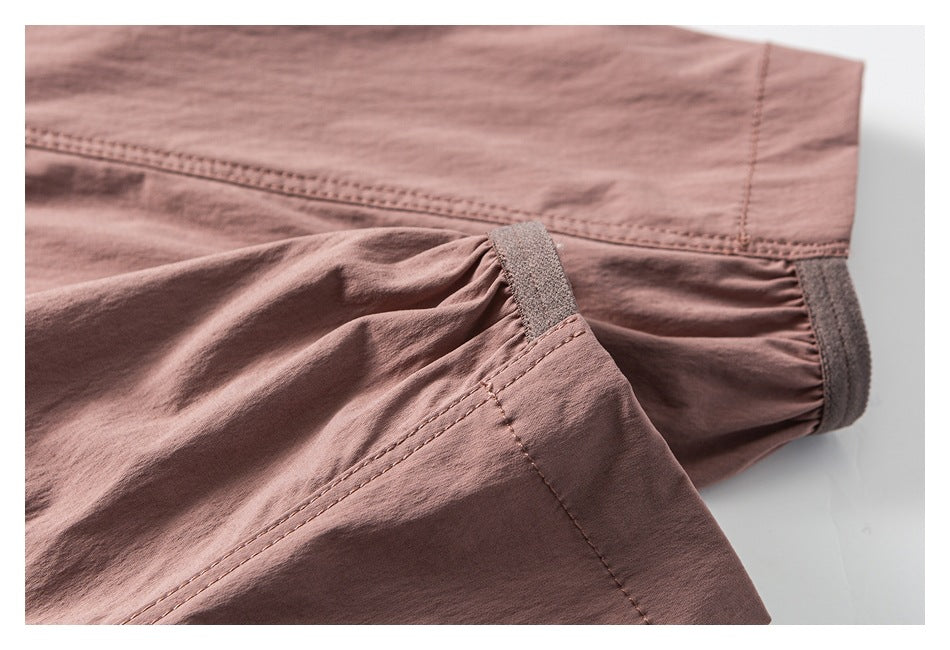 Close-up of a dusty mauve jacket sleeve cuff with gathered fabric, hook-and-loop tabs, and double stitching.