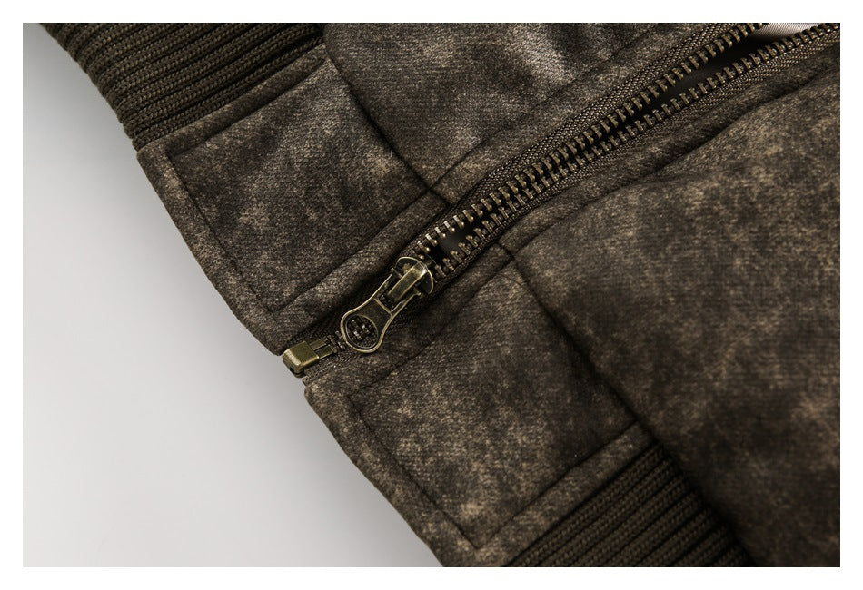 Close-up of a metal zipper, stitched panels, and rib-knit cuff on a mottled brown jacket.