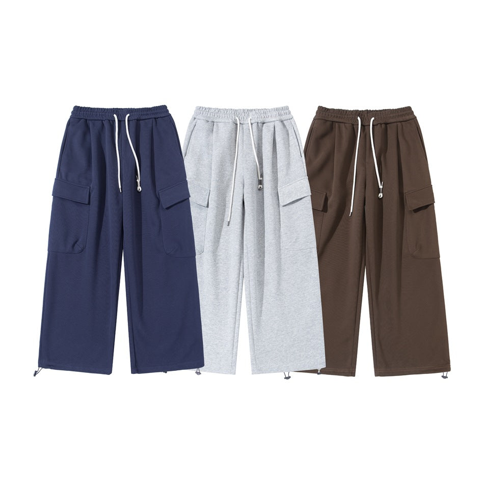 Three front views of wide-leg cargo sweatpants in navy, light gray, and brown, with drawstring waists and side pockets.