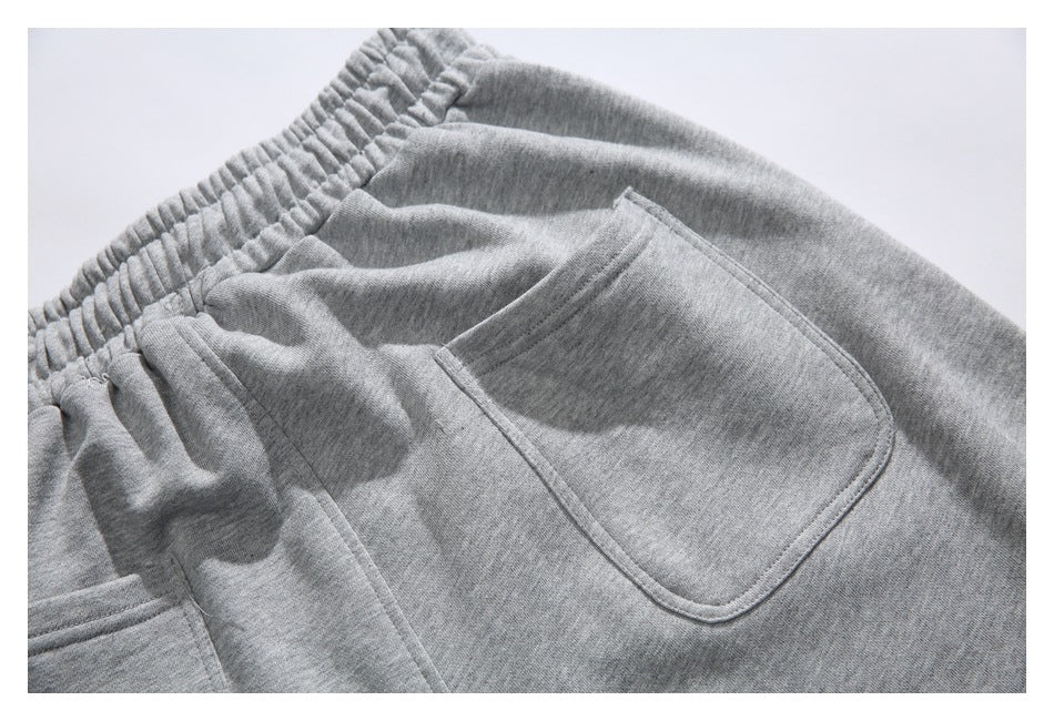 Close-up of the back of gray sweatpants, showing the elastic waistband and patch pockets.