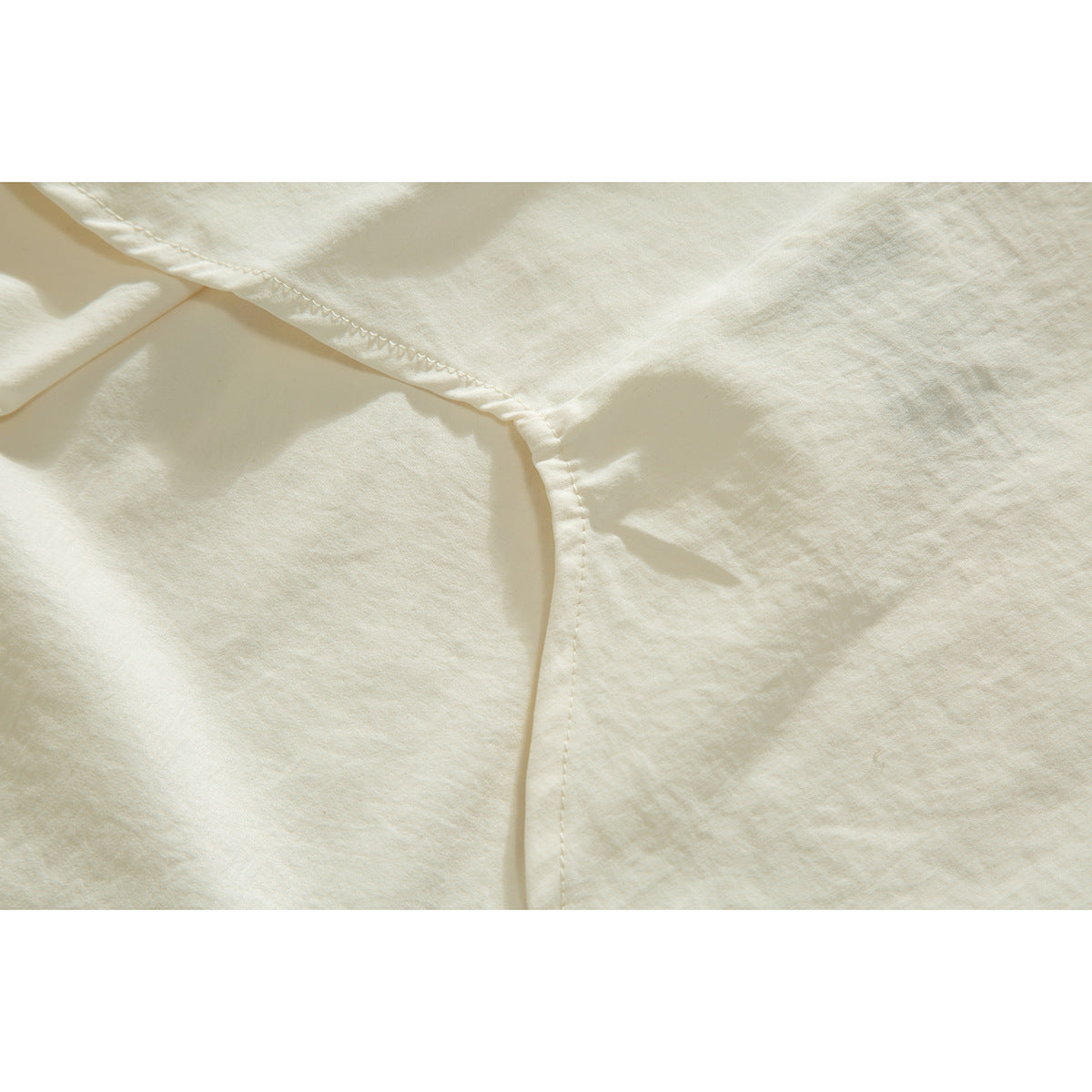Close-up of the ivory shirt's sleeve seam and stitching.