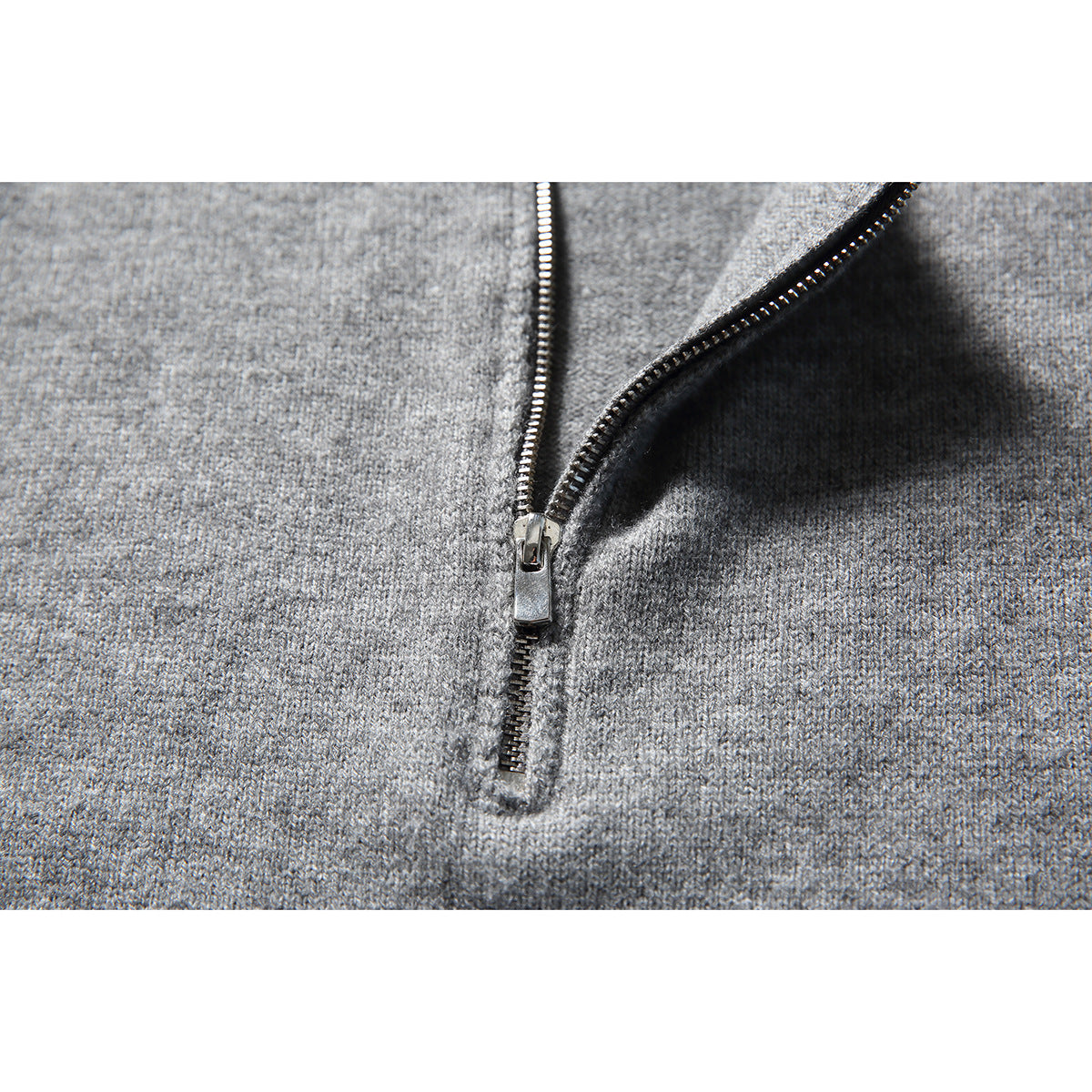 Close-up of a silver zipper on a gray knit sweater.