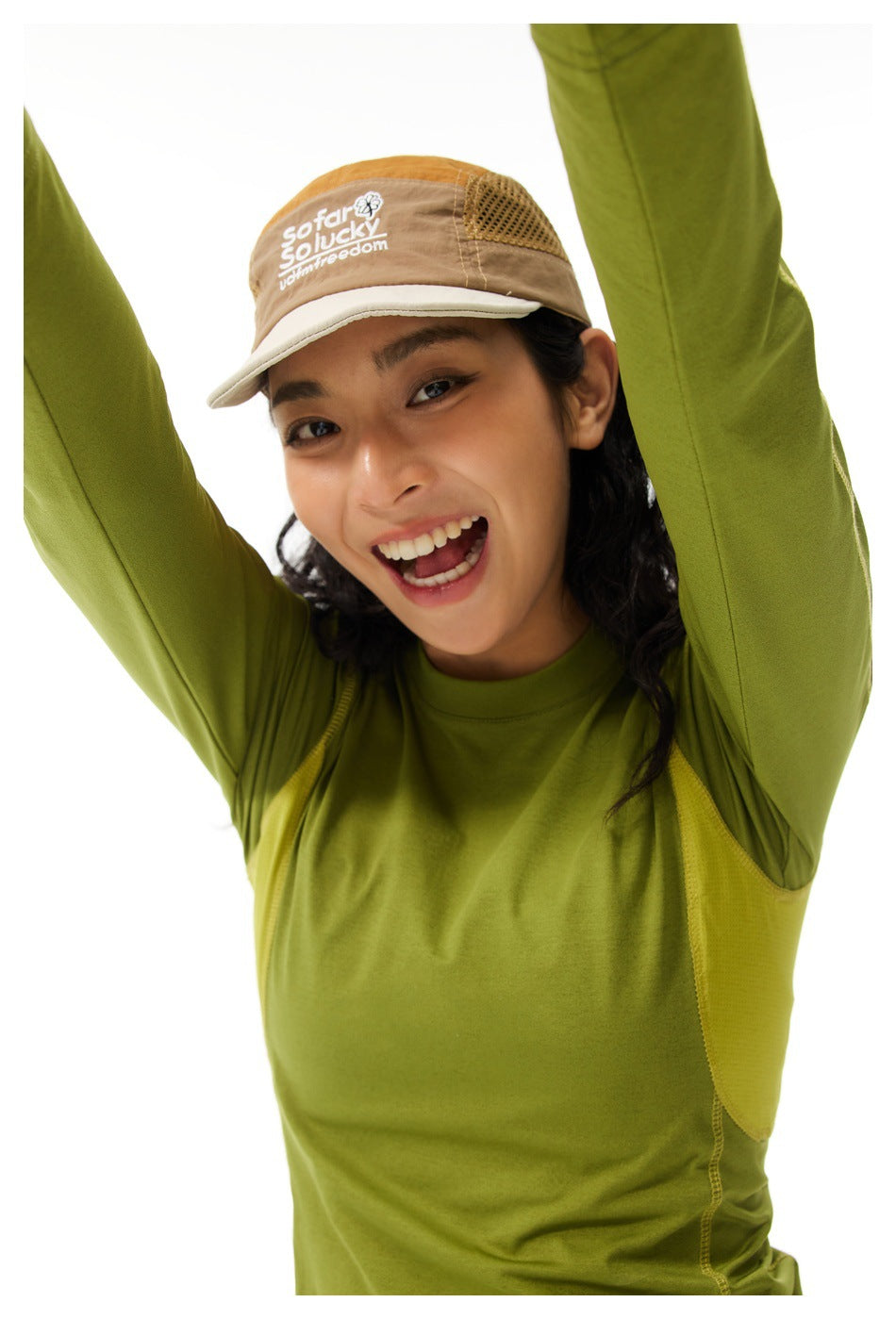 Close-up of a model in a green long-sleeve top with contrasting mesh underarm panels and a tan cap.