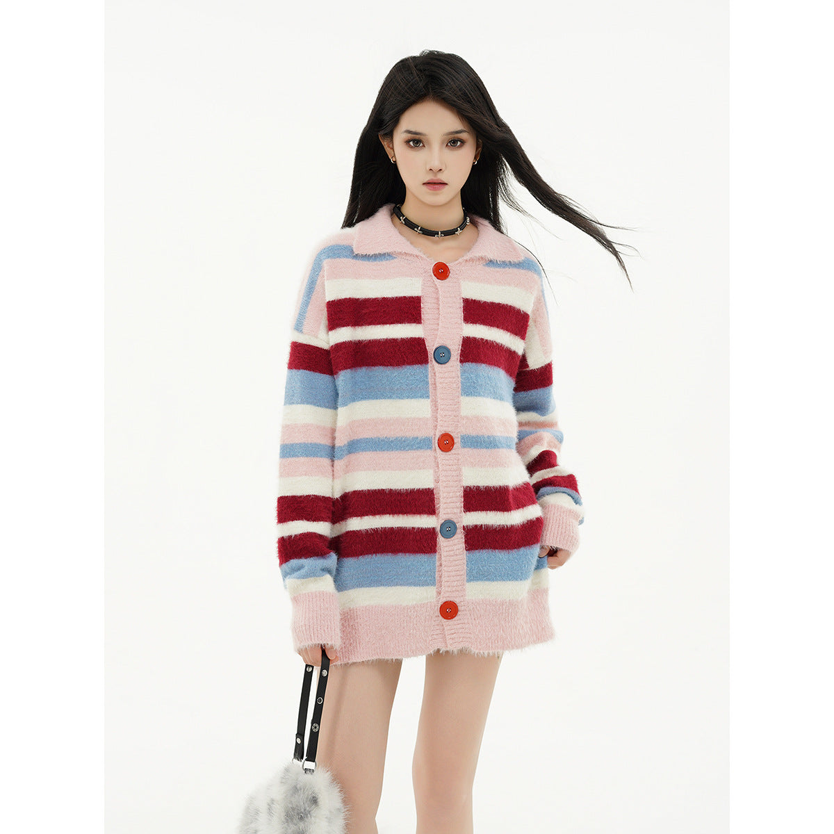 Model wearing a long pink cardigan with red, blue, and cream horizontal stripes and colorful buttons.