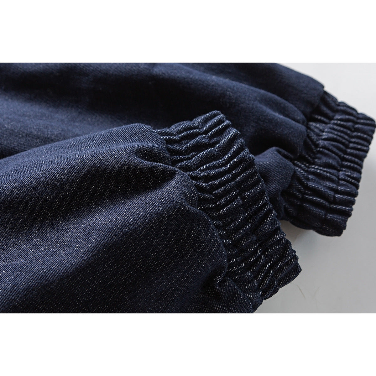 Close-up of gathered elastic cuffs on the dark indigo jacket sleeves.