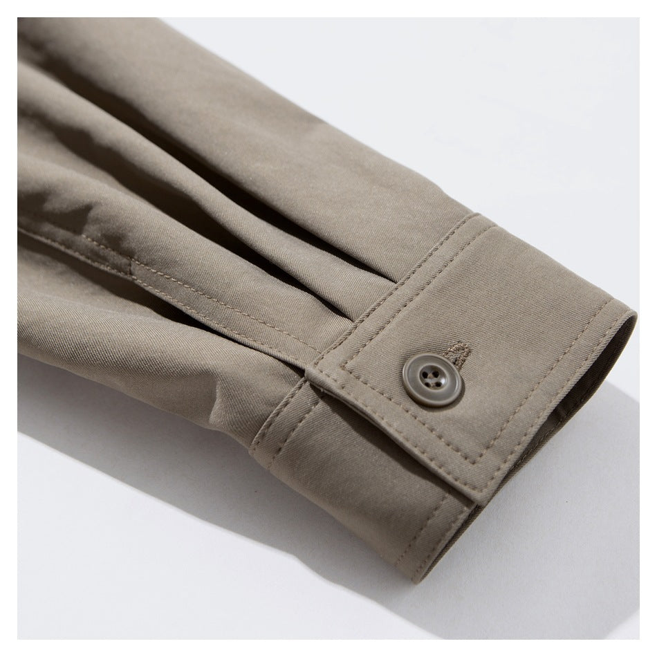 Close-up of a taupe sleeve cuff with a round button and stitched buttonhole.