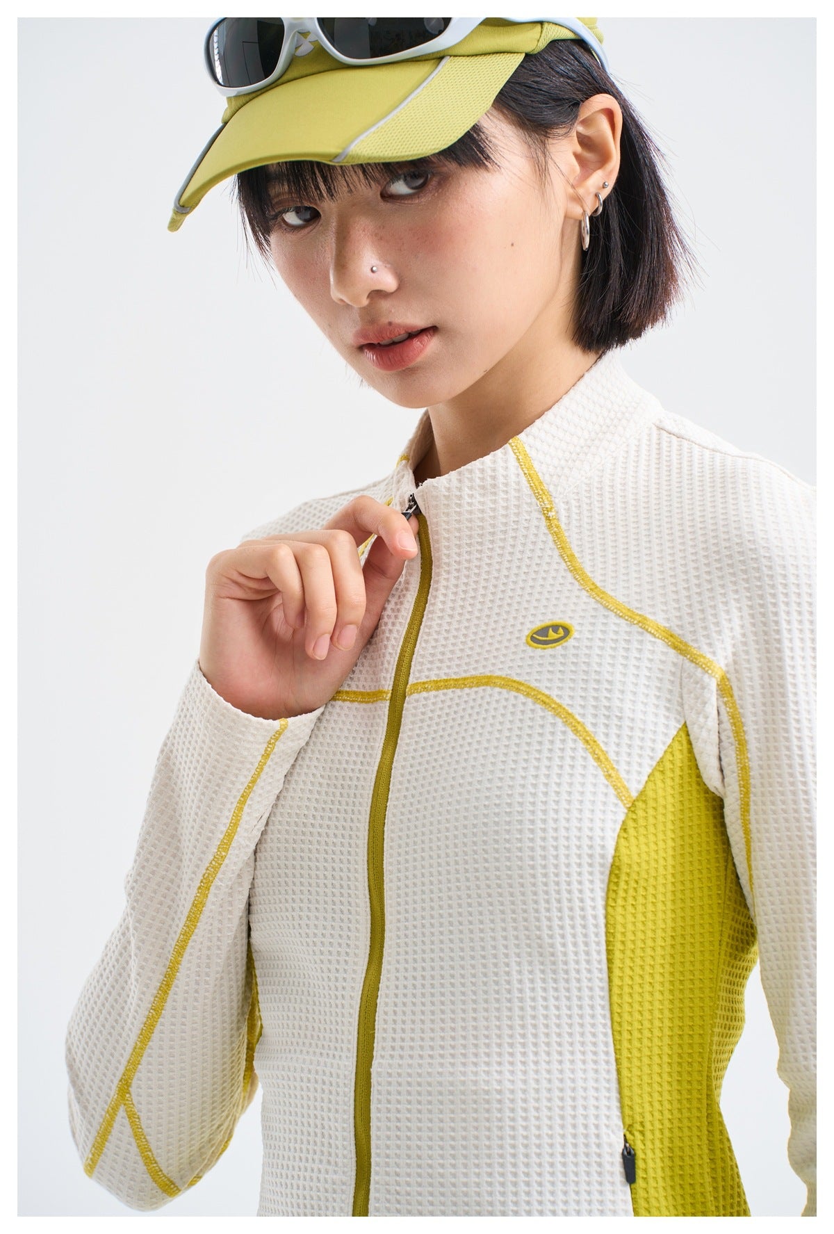 Close view of a model wearing a white textured zip-up jacket with yellow trim and side panels.