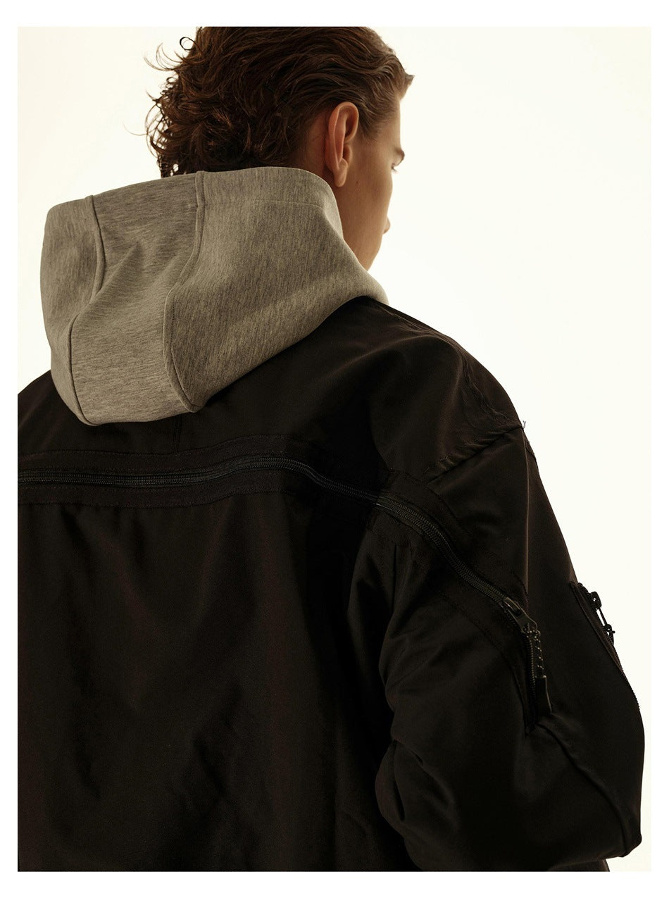 Back view of a person wearing a black jacket with a gray hood layer and a zipper across the back and sleeve