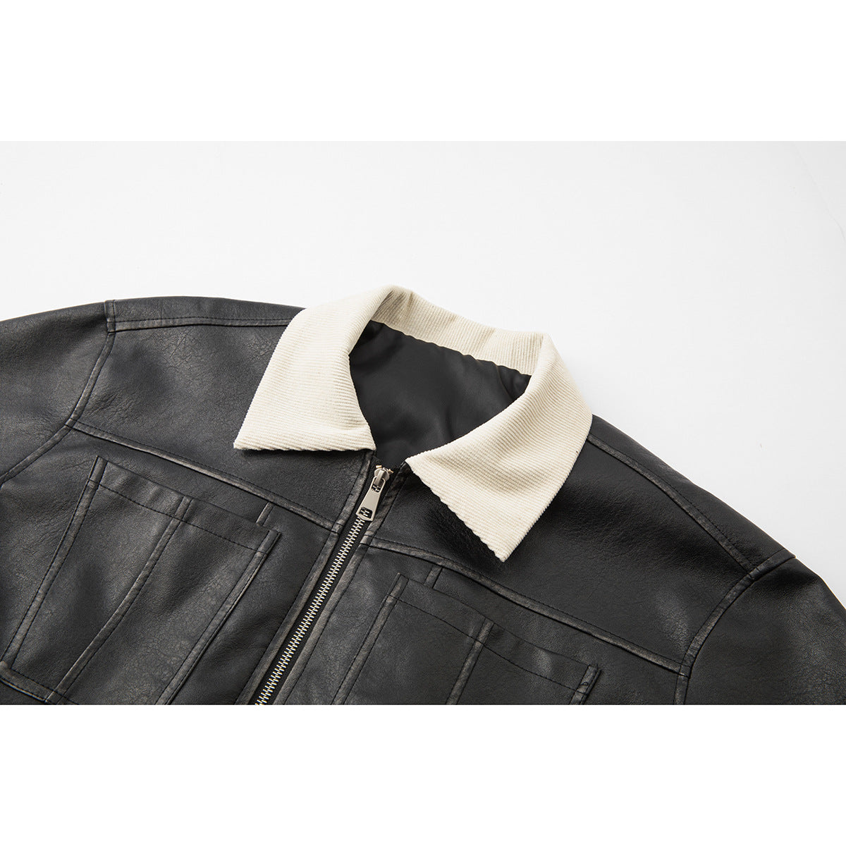 Close-up of a black jacket's front with a cream ribbed pointed collar, chest pockets, and silver zipper.