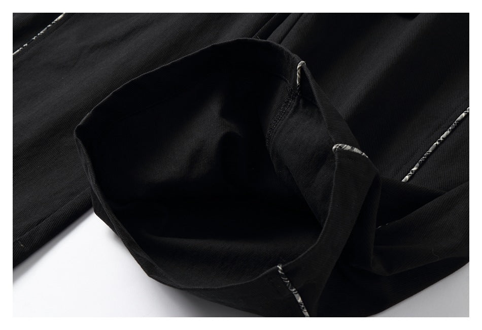Close-up of a black trouser pocket opening and interior, with narrow plaid piping nearby.