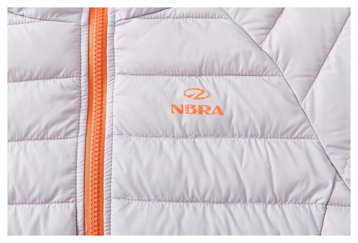 Close-up of an orange zipper and NBRA logo printed on the pale lavender quilted jacket.