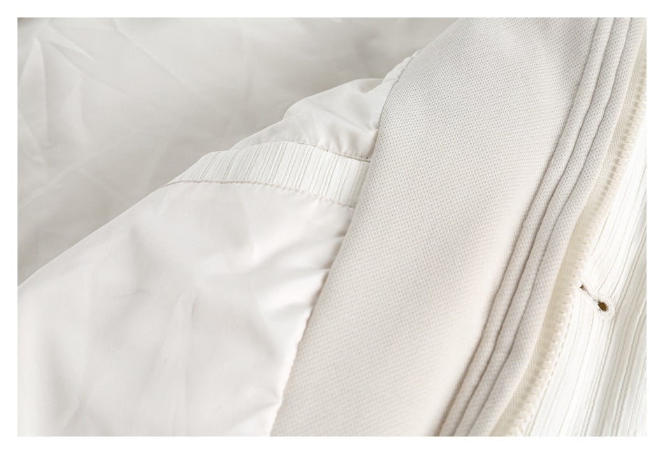 Close-up of the ivory garment's interior, showing smooth lining, a ribbed seam, and textured trim.