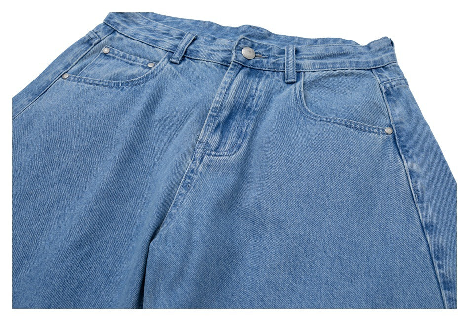 Cropped front view of light blue jeans showing the waistband, button fly, belt loops, and pockets.