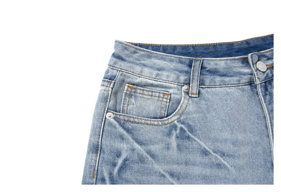 Close-up of the front coin pocket and curved pocket stitching on light-wash denim shorts.