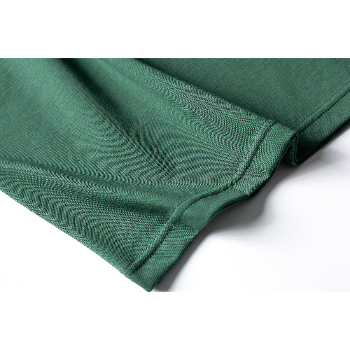 Close-up of the stitched bottom hem on a dark green T-shirt.