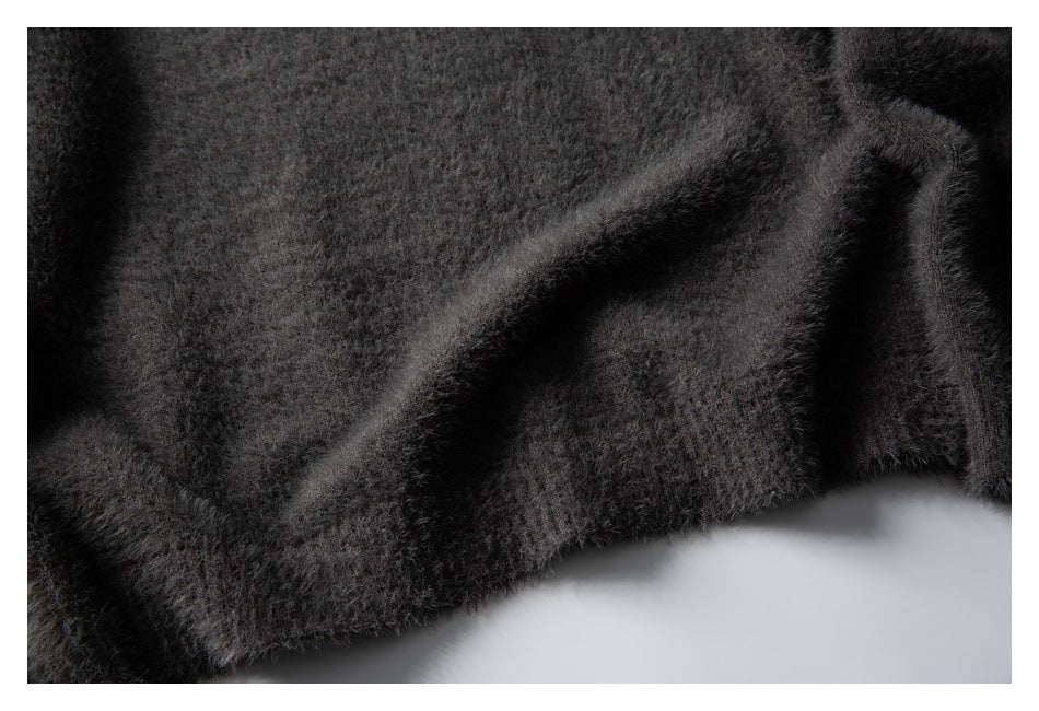 Close-up of charcoal gray fuzzy knit fabric with a folded, stitched edge.