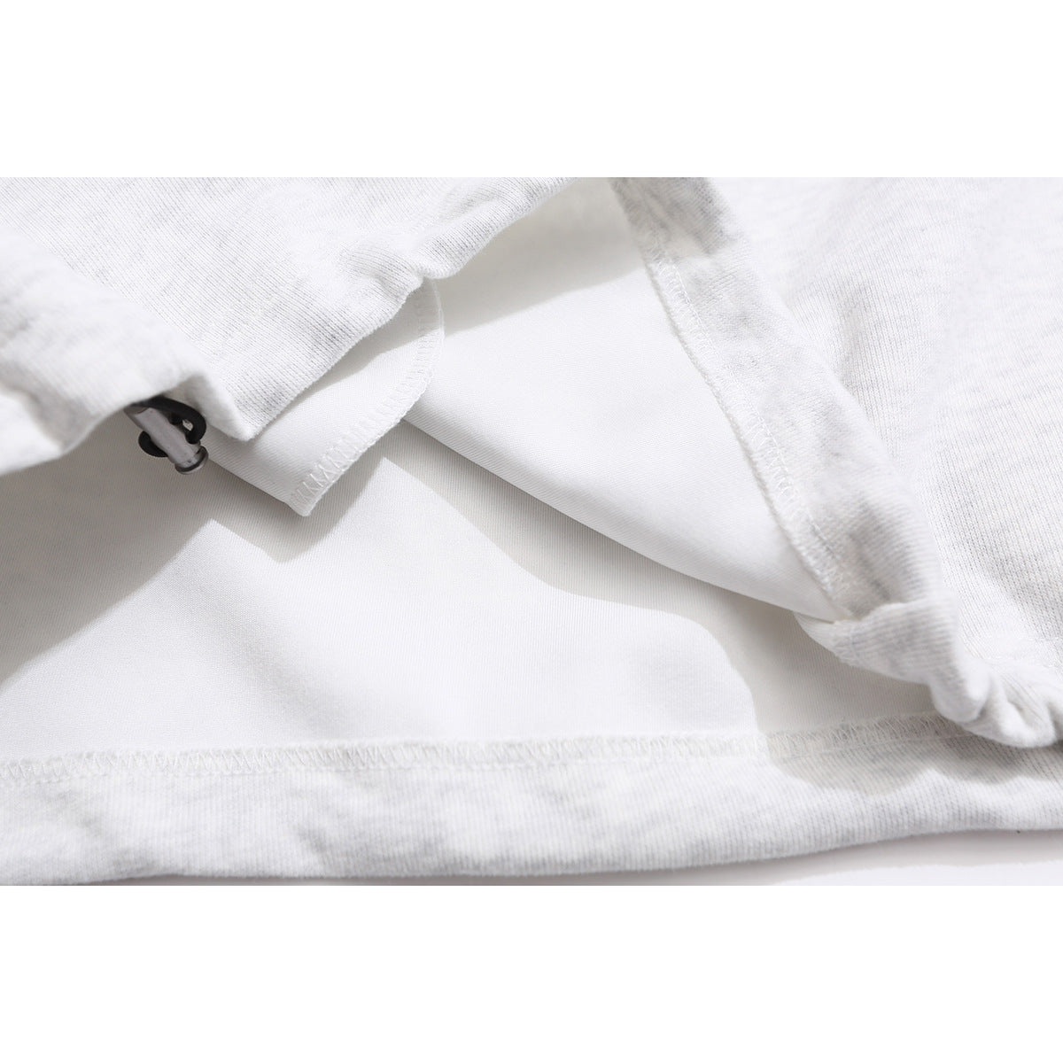 Close-up of the inside seams and lining of a light gray hoodie.