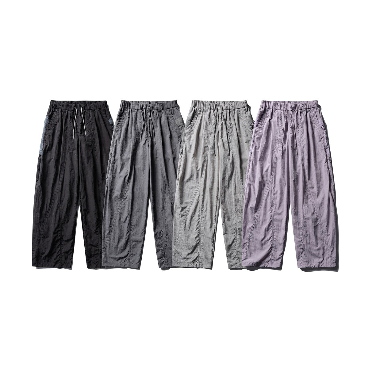 Four pairs of loose drawstring pants shown side by side in black, charcoal, light gray, and lavender.