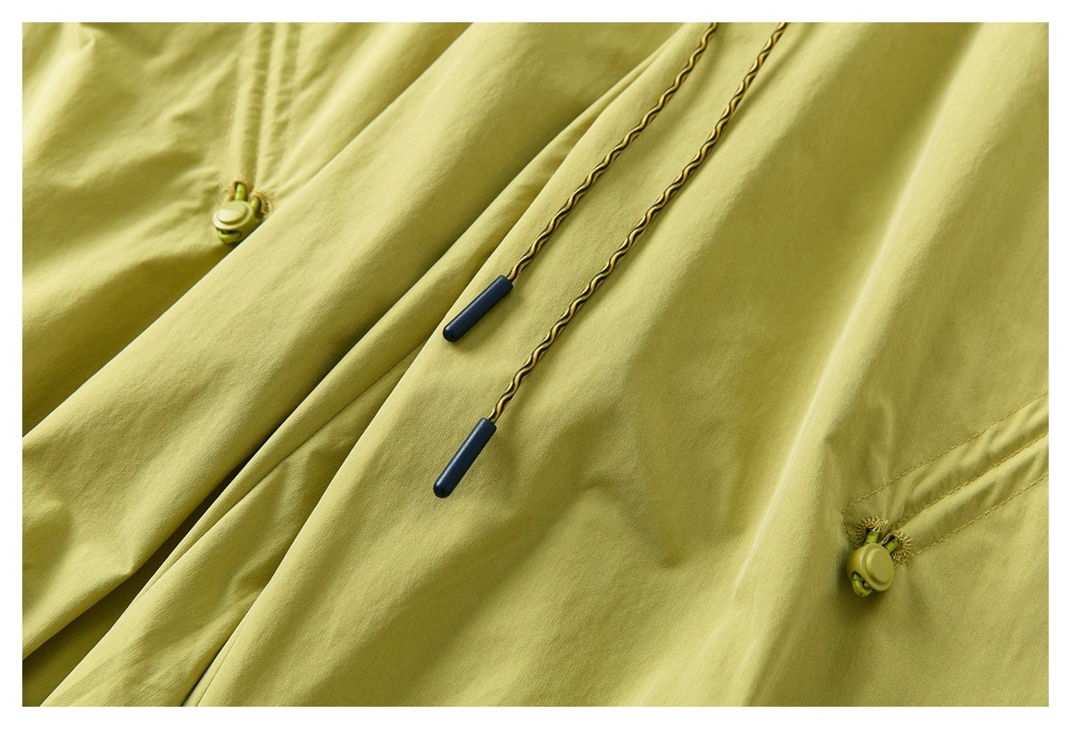 Close-up of yellow-green pants showing twisted drawstrings with dark tips and a zippered pocket.