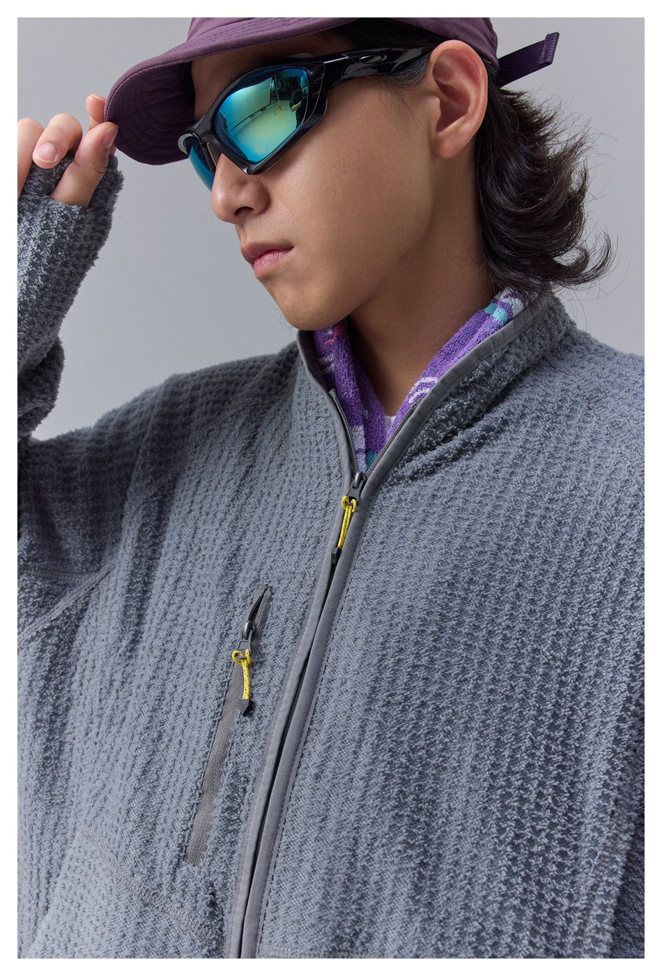 Close-up of a gray textured jacket showing its front zipper, chest pocket zipper, and collar.