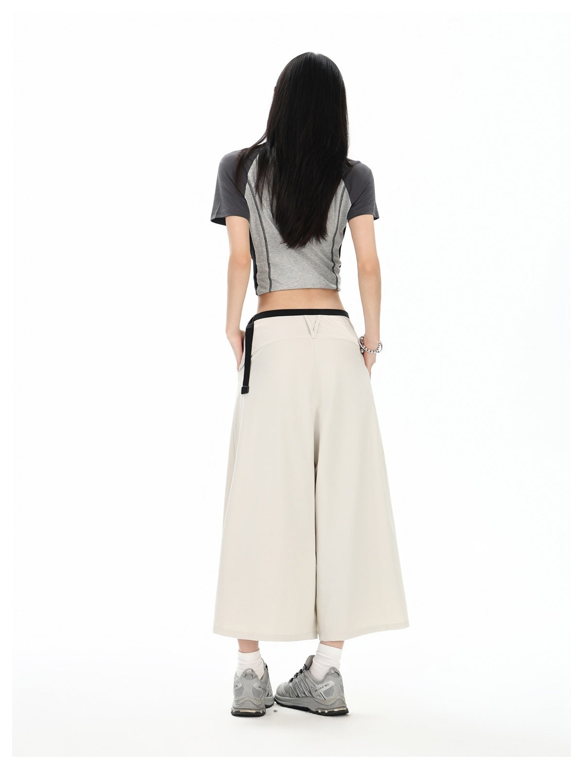Model wearing the light beige skirt from the back, showing its wide, flowing silhouette and black waistband.