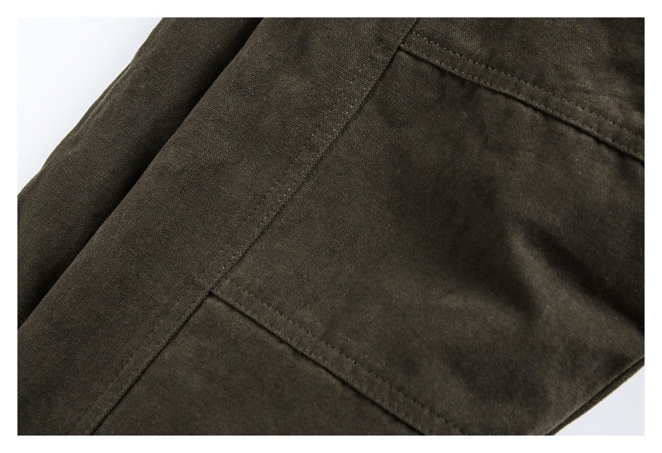 Close-up of a dark olive-brown garment with a large stitched patch pocket and visible seams.