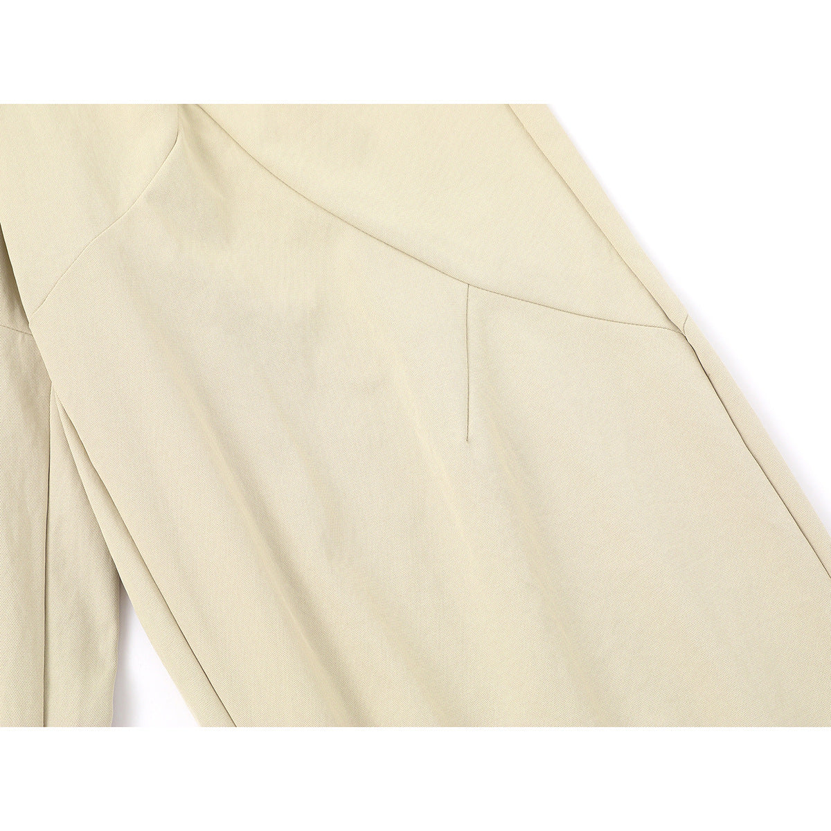 Close-up of the cream trousers' curved panel seams and fabric.