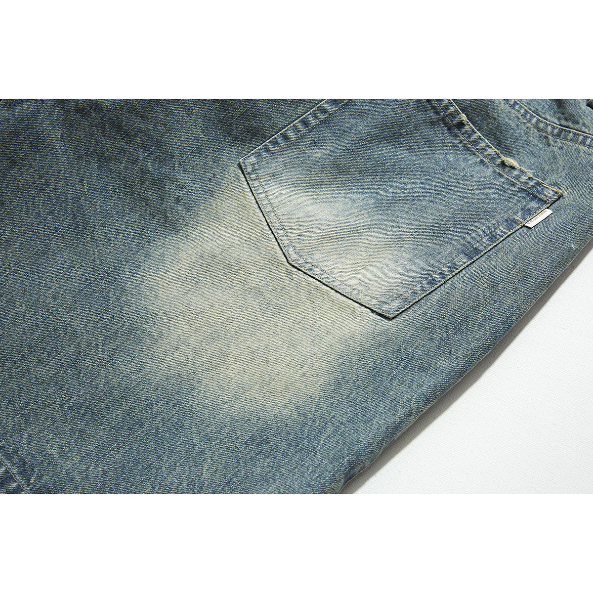 Close-up of a faded blue jeans back pocket with contrast stitching.