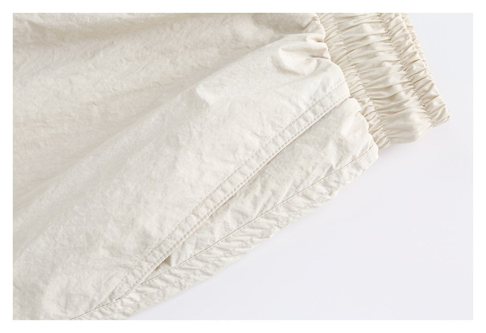 Close-up of cream pants showing a stitched seam and gathered elastic edge.
