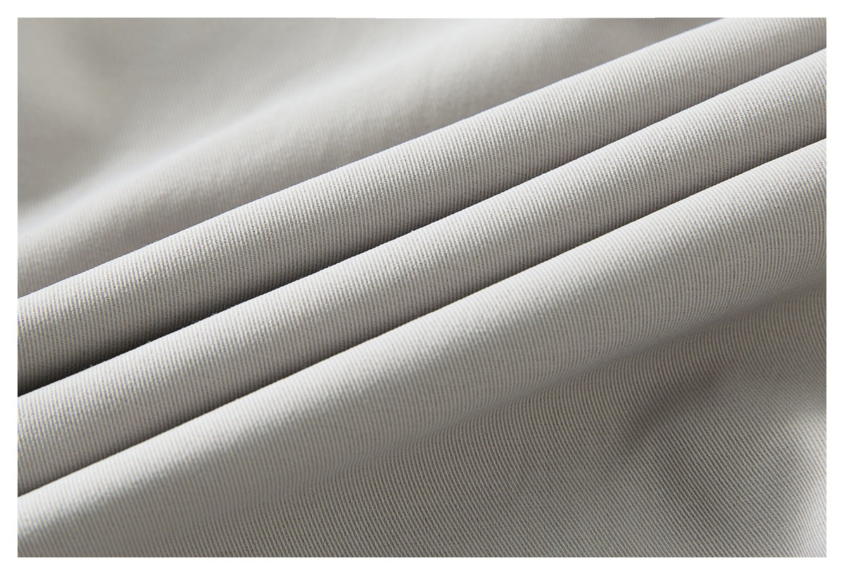 Macro view of light gray trouser fabric folded to show its fine diagonal weave.
