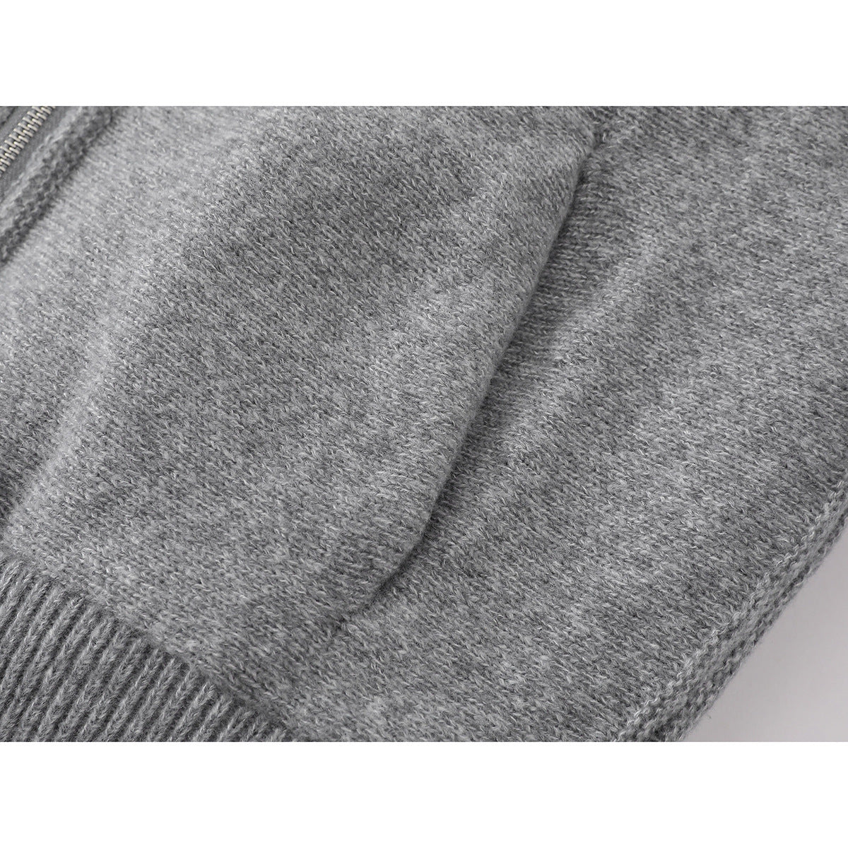 Close-up of the gray knit jacket's textured fabric and front pocket edge.