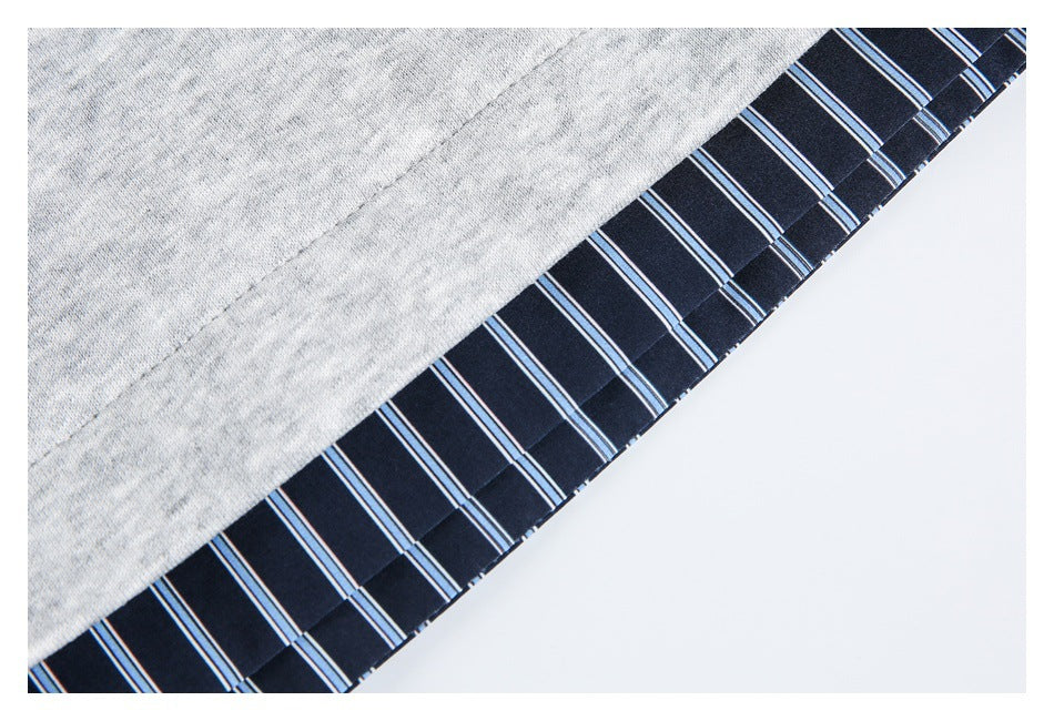 Close-up of a light gray garment edge finished with dark navy fabric striped in blue and white.