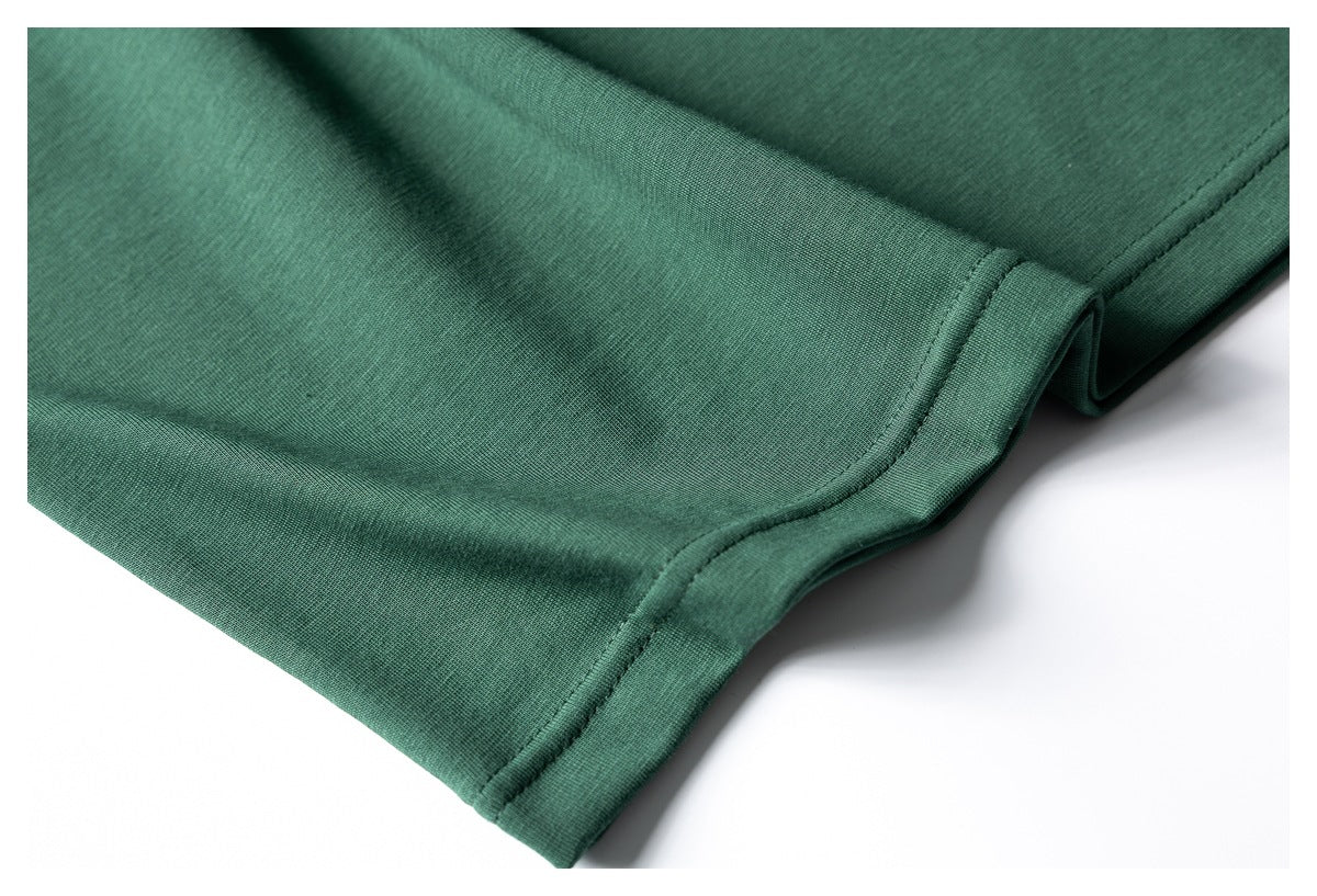 Close-up of the dark green T-shirt's side seam and stitched lower hem.