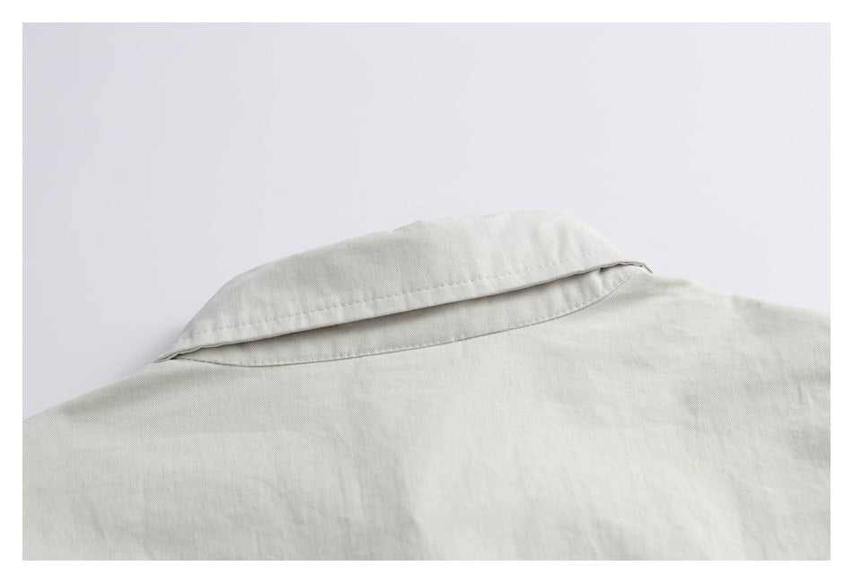Close-up of the collar and shoulder of an off-white garment, showing the stitching and fabric texture.